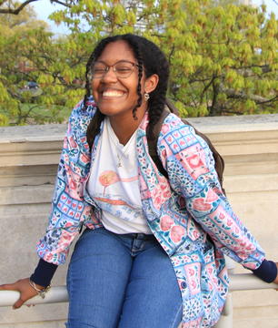 Person (Dara Badon '22) with two braids, wearing a patterned jacket with light pink and blue colors, and smiling